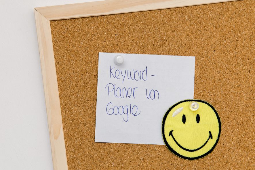 Website Texte schreiben: Korkenpinnwand mit Smiley-Bild Begleitbild zu Abschnitt Website frisch und sichtbar machen: Korkenpinnwand mit Notiz Keyword-Planner und Smiley-Bild