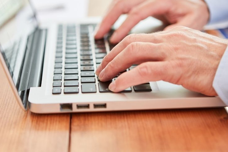 Blog schreiben mit KI: Männerhände auf weisser Tastatur Begleitbild zu